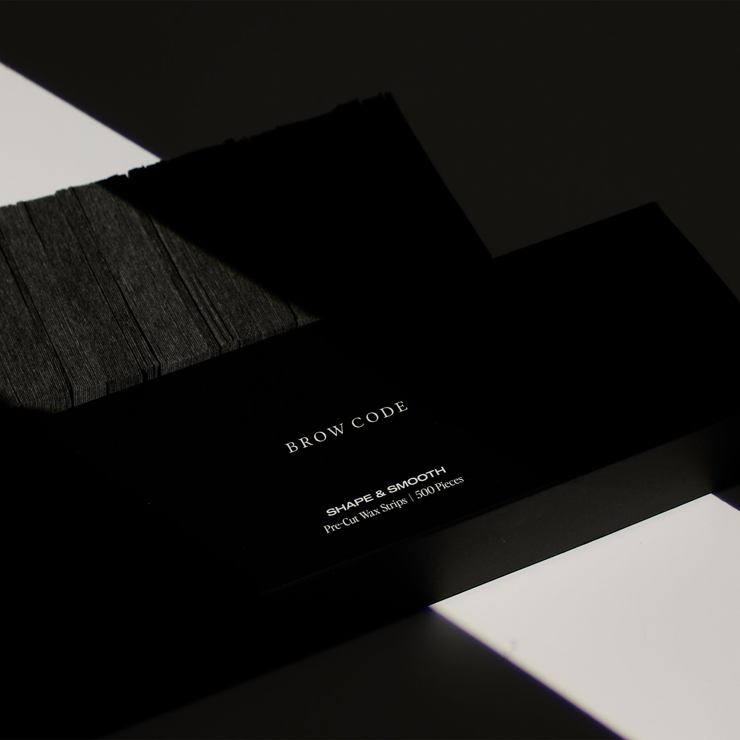 Brow Code's Pre-Cut Wax Strips packaging displayed beside a set of the pre-cut wax strips, showing both the product and its outer packaging