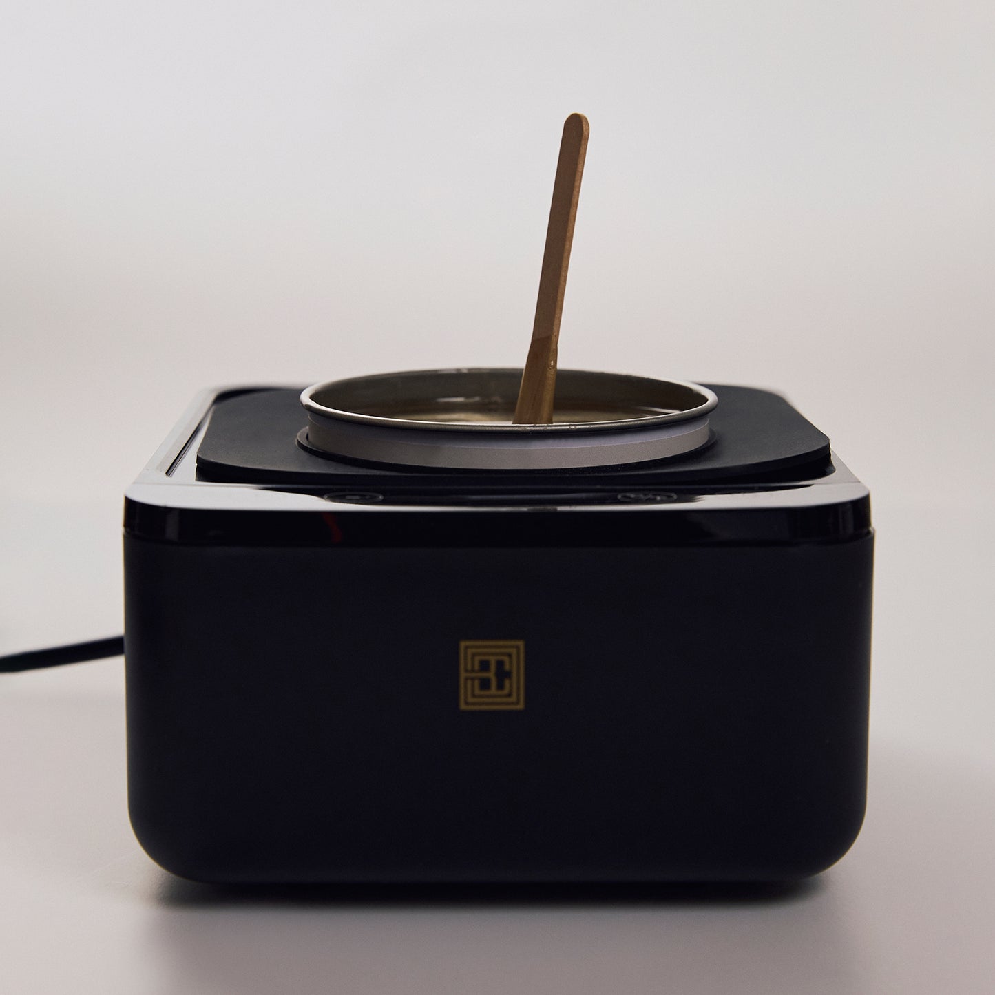 Brow Code’s Wax Collar fitted around a wax warmer, preventing wax drips and keeping the station clean