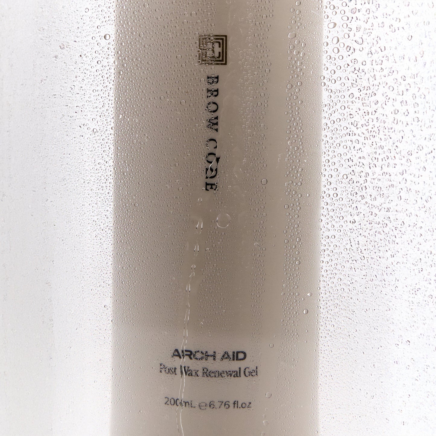 Brow Code Arch Aid Post Wax Renewal gel bottle behind a foggy, wet surface
