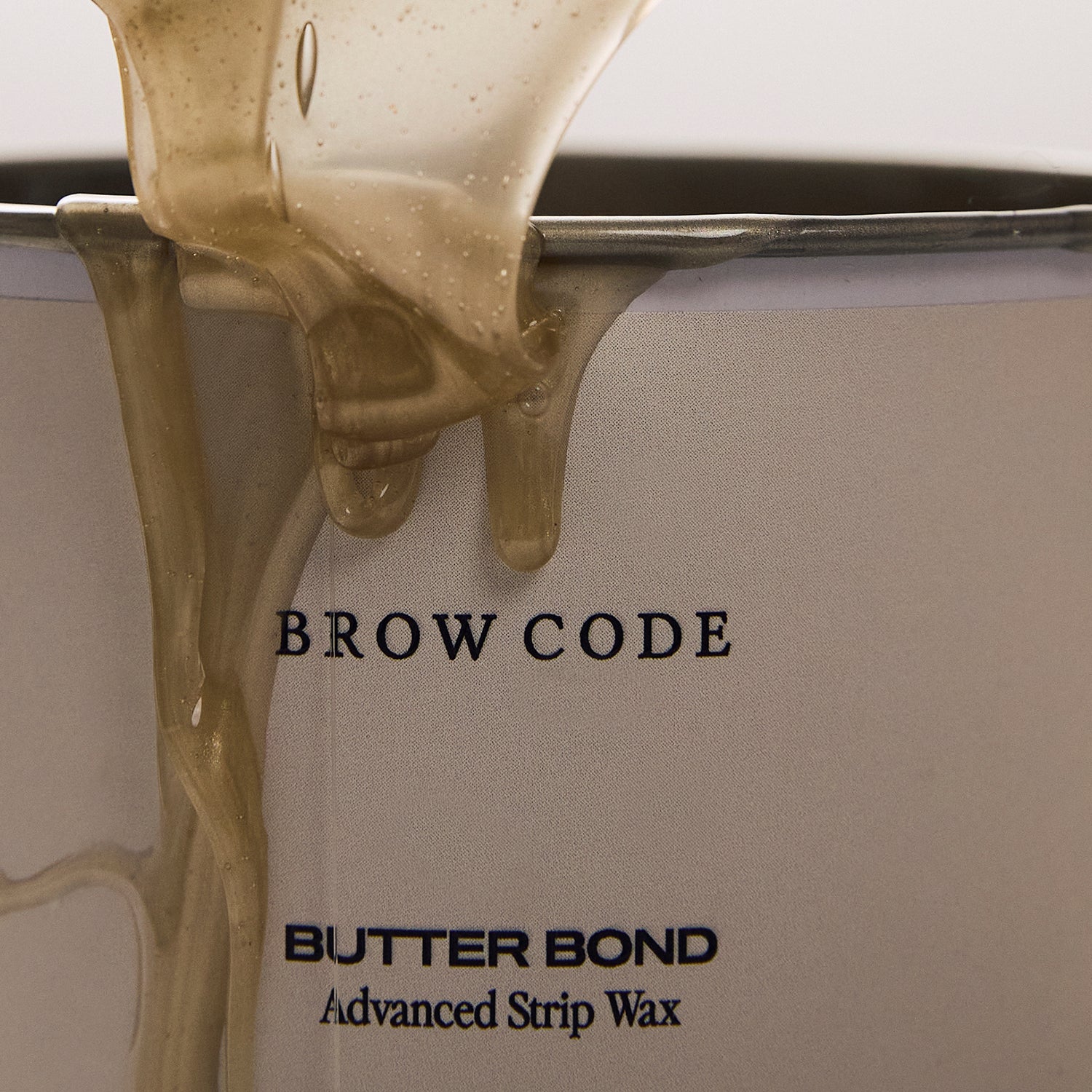 Butter Bond wax dripping slowly down the outer edge of a wax pot, showcasing its rich, buttery texture and smooth consistency