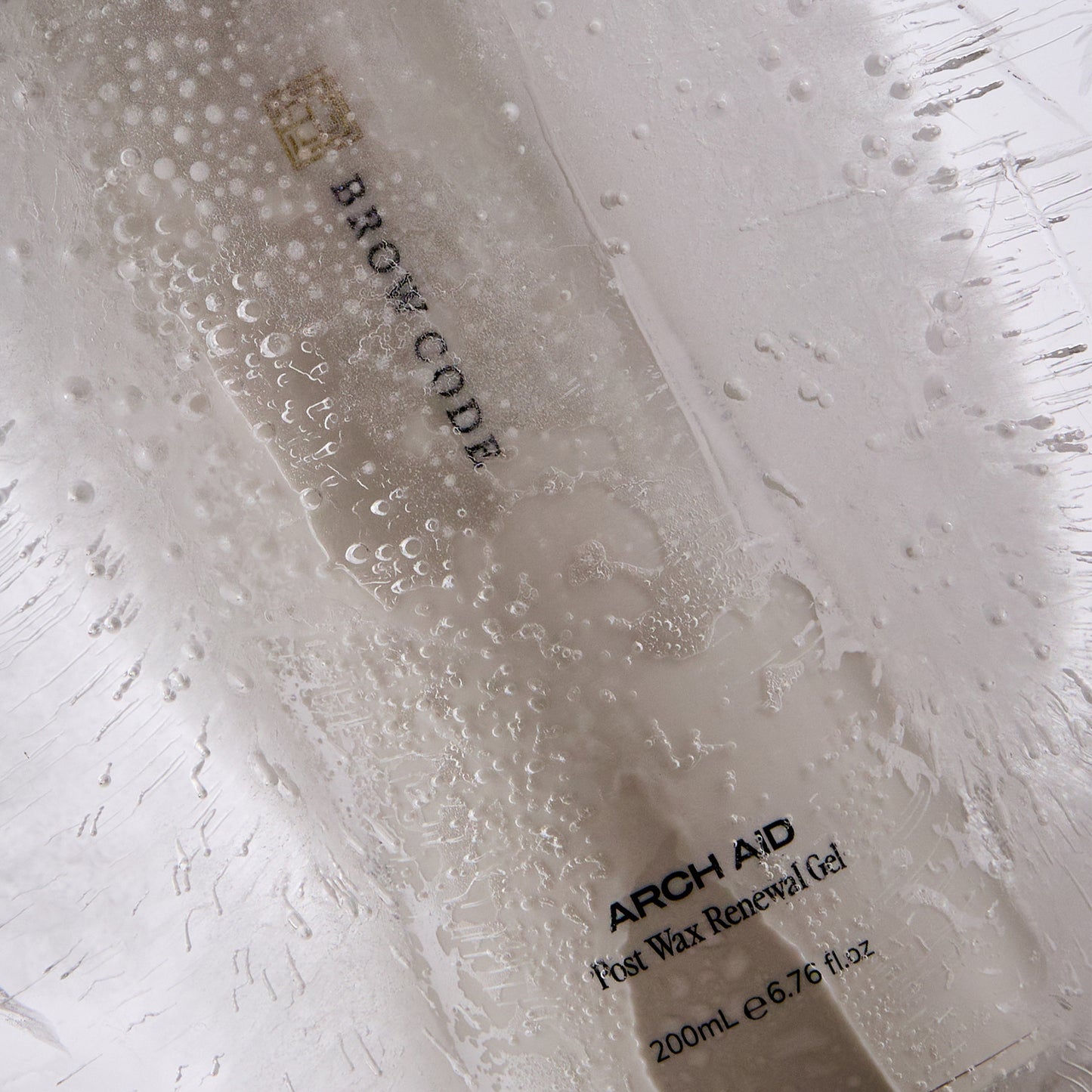 Brow Code Arch Aid bottle encased in ice with air bubbles and frost texture